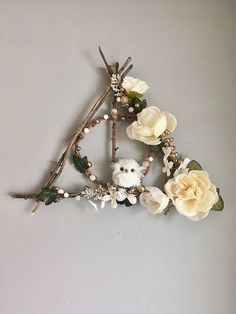 an owl sitting on top of a twig with flowers and branches in the shape of a triangle