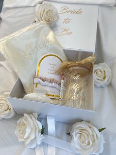 a white box with some flowers and a candle in it next to a couple's wedding rings