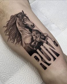 a black and white horse tattoo on the right leg, with the word run written below it