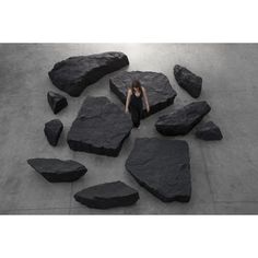 a woman is sitting on some rocks in the middle of a floor that has been made out of stones