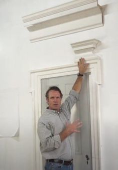 a man standing in front of a doorway holding his hand up to the door handle