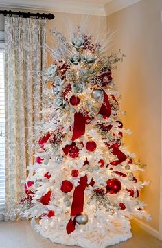 a white christmas tree decorated with red and silver ornaments