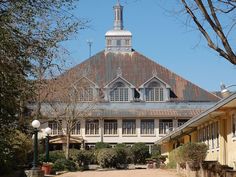 an old building with a steeple on top and trees in the foreground behind it