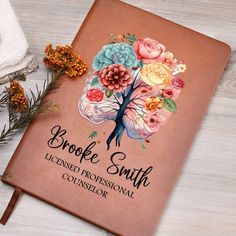 a brown book with flowers on it and the words brooke smith is next to an orange flower