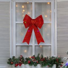 a red bow on the window sill with christmas lights in the windowsill behind it