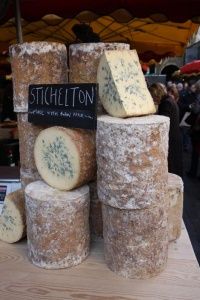 several different types of cheese stacked on top of each other at an outdoor food market