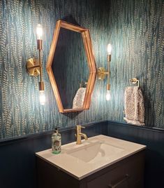 a bathroom with blue and gold wallpaper, vanity mirror and light fixture in it