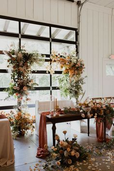 an arrangement of flowers and greenery decorates the back of a wedding reception table