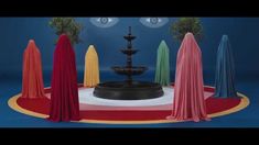 there are many different colored umbrellas on the ground in front of a water fountain