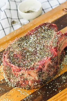 a steak on a cutting board with seasoning sprinkled over it and spices