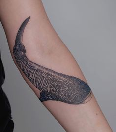 a person with a tattoo on their arm has a whale tooth in the shape of a knife