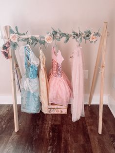 three dresses are hanging on a clothes rack with flowers and leaves in the foreground