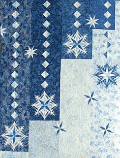 a blue and white quilt with snowflakes on the front, stars in the back