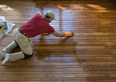 a man in red shirt and white pants on wooden floor