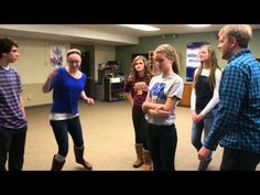 a group of young people standing around each other in a room with one person holding a wii controller