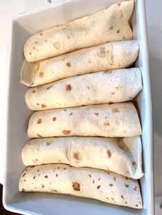 four tortillas in a white dish on a table