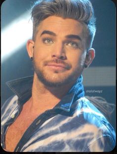 a close up of a person wearing a blue shirt and piercings on his ear