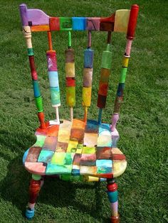 a chair made out of crayons sitting on top of a grass covered field