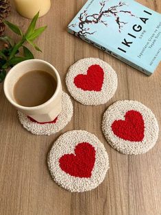 four red and white heart coasters next to a cup of coffee on a table