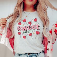 This Sweet on You lollipop candy heart t-shirt is a gift for yourself (or a sweetheart) on Valentine's Day or any time of year. Unisex sizing. Order up for an oversized look. DESCRIPTION * Our shirts are soft and comfortable and the styling possibilities are endless. Roll up the sleeves, tie a side knot, front tuck, or wear it while lounging around the house. * 100% Airlume combed and ringspun cotton (fiber content may vary for different colors). * Ribbed knit collars to bolster shaping.  * The shoulders have taping for better fit over time. Dual side seams hold the garment's shape for longer.  * Fitting is unisex, runs true to size. CARE INSTRUCTIONS * Cotton shirts will shrink about half a size (give or take). Recommended to wash inside out with cold water. Air or tumble dry. Do not blea Heart Sucker, Valentine Graphic, Valentines Graphic Tee, Teacher Aesthetic, Lollipop Candy, Front Tuck, Heart T Shirt, Heart Shirt, Cotton Shirts