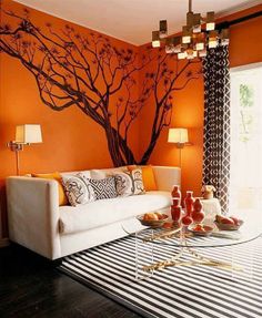 the living room is decorated in orange and white colors with a tree painted on the wall