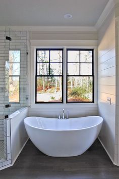 a large white bath tub sitting under two windows