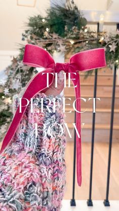 a hand holding a pink ribbon with the words the perfect love on it in front of a christmas tree