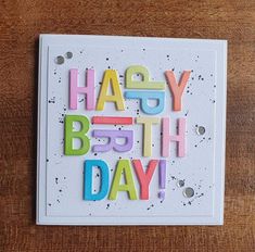 a card with the words happy birthday written in multicolored letters on top of it