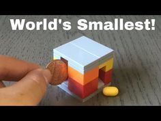 a person holding a penny in front of a small toy cube with the word world's smallest on it