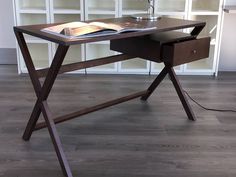 a desk with a book and lamp on it in front of a bookshelf