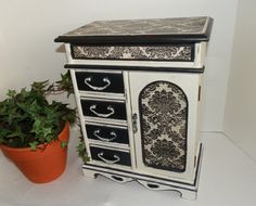 a white and black cabinet next to a potted plant