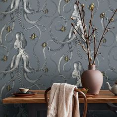 an octopus wallpaper design in grey and gold on a dining room table next to a vase with flowers