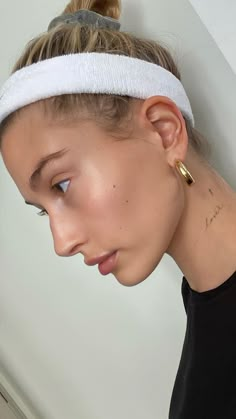 a woman wearing a headband and looking down at her cell phone in front of her face