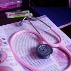 a pink stethoscope sitting on top of an open book