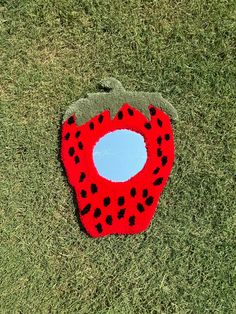 a red and black object laying on top of green grass next to a hole in the ground