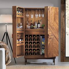 an armoire with wine glasses and bottles in it is next to a couch that has a rug on the floor