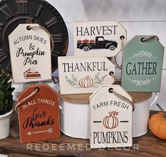 some white buckets filled with different types of pumpkins and other items on top of a wooden table