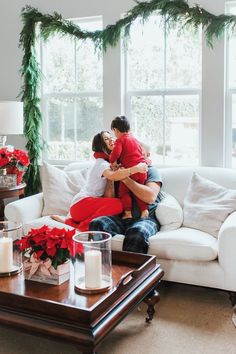 two people sitting on a couch in front of a window with christmas decorations around them