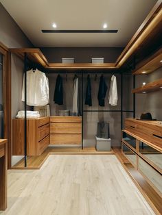 an empty walk in closet with clothes hanging on the walls and wooden flooring,