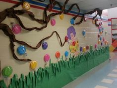 a wall decorated with balloons and streamers in a school hallway or playroom for children