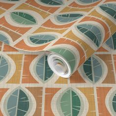 an orange and green wallpaper with leaves on it's side, next to a roll of tape