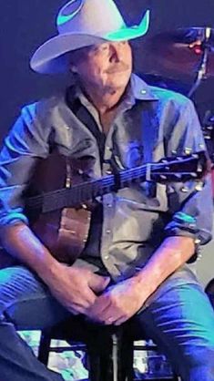 a man with a cowboy hat sitting in front of a guitar