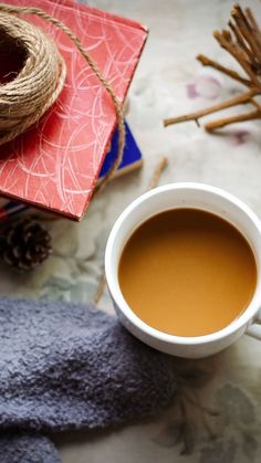 a cup of hot chocolate next to some cinnamon sticks and twine on a table