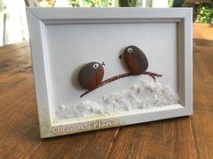 two birds sitting on top of a branch in the snow under a shadow box frame