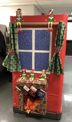 an office cubicle decorated for christmas with elfs on the windowsill and presents