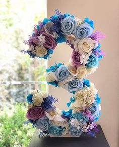 the letter e is made up of flowers and blue, purple, and white blooms