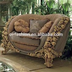 an ornate couch with pillows on it in the middle of a room filled with potted plants