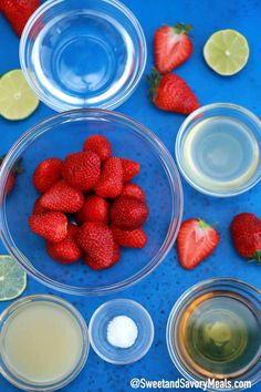 strawberries, lemons, and other ingredients are in bowls on a blue surface