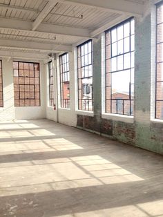 an empty room with large windows and brick walls