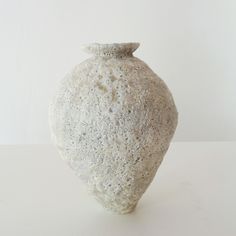 a white vase sitting on top of a table next to a white wall and floor